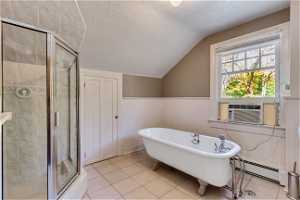 Upstairs Bathroom featuring a baseboard heating unit, independent shower and bath, tile flooring, and vaulted ceiling