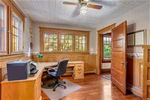 Home office featuring a baseboard heating unit, ceiling fan, and light hardwood / wood-style floors