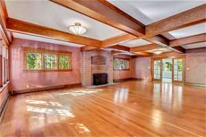 Unfurnished living room with a healthy amount of sunlight, light hardwood / wood-style floors, and a brick fireplace