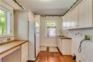 Kitchen featuring white cabinets, light hardwood / wood-style floors, and white fridge