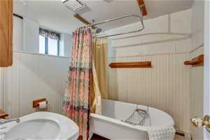 Basement Bathroom featuring shower / bath combo with shower curtain, sink, and a baseboard heating unit