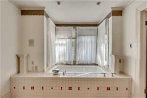 Master Bathroom with tiled bath, a healthy amount of sunlight, and crown molding