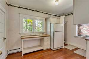 Kitchen with baseboard heating, white refrigerator, and hardwood / wood-style flooring
