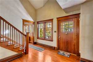 Foyer entrance with high vaulted ceiling, light wood-type flooring, and a baseboard heating unit