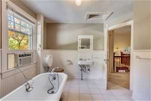 Upstairs Bathroom featuring tile floors, sink, a textured ceiling, and a bath to relax in