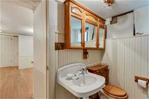 Basement Bathroom with toilet, sink, and hardwood / wood-style floors