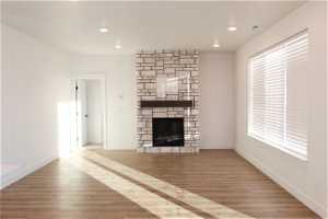 Unfurnished living room featuring a stone fireplace and light hardwood / wood-style floors