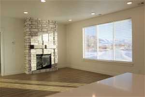 Unfurnished living room with dark wood-type flooring and a stone fireplace
