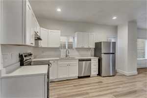 Kitchen with plenty of natural light, white cabinets, sink, and appliances with stainless steel finishes