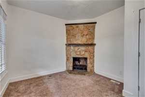 Unfurnished living room featuring a fireplace, carpet floors, and plenty of natural light