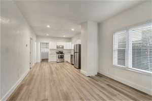 Kitchen with light hardwood / wood-style floors, stainless steel appliances, and white cabinetry