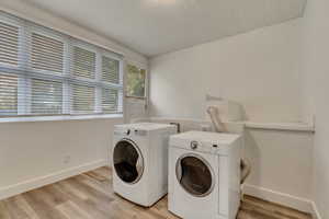 Laundry room with washing machine and dryer and light hardwood / wood-style flooring