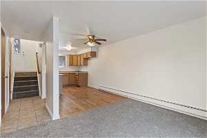 Unfurnished living room featuring ceiling fan, a baseboard radiator, and light tile floors