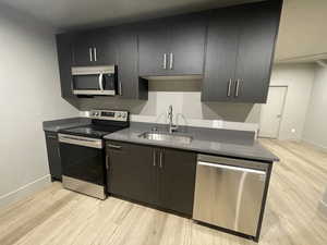 Kitchen with light hardwood / wood-style flooring, sink, and appliances with stainless steel finishes