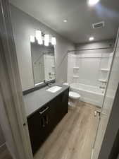 Full bathroom featuring toilet, vanity, washtub / shower combination, and hardwood / wood-style flooring