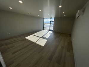 Spare room featuring dark wood-type flooring, a wall unit AC, and expansive windows