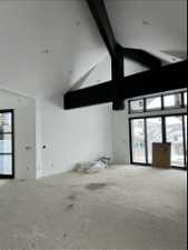 Unfurnished room with high vaulted ceiling, plenty of natural light, and beam ceiling