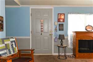 Carpeted entryway featuring crown molding