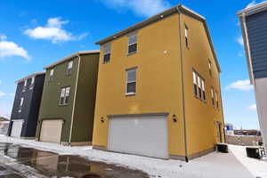 View of snow covered exterior featuring a garage and central AC