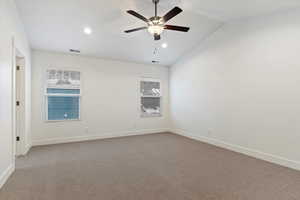 Spare room with vaulted ceiling, light carpet, and ceiling fan