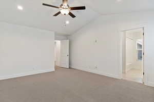 Empty room featuring vaulted ceiling, light colored carpet, and ceiling fan