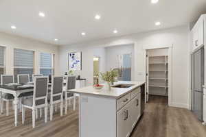 Kitchen featuring dishwasher, white cabinets, dark hardwood / wood-style flooring, sink, and an island with sink