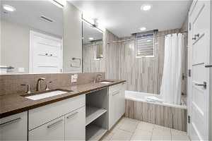 Bathroom with tasteful backsplash, tile floors, shower / bath combo, and dual bowl vanity