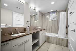 Bathroom featuring shower / bath combination with curtain, tile flooring, double sink vanity, and tasteful backsplash
