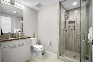 Bathroom with toilet, an enclosed shower, oversized vanity, and tile flooring