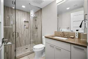 Bathroom featuring a shower with shower door, tasteful backsplash, toilet, oversized vanity, and tile floors