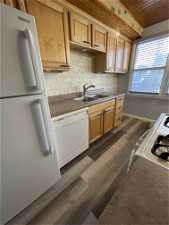 Kitchen with dark hardwood / wood-style floors, sink, white appliances, and tasteful backsplash