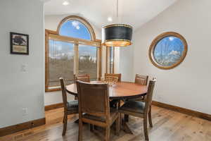 Dining room with vaulted ceiling and light hardwood / wood-style flooring