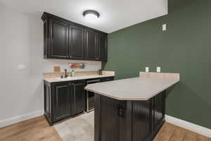 Kitchen with beverage cooler, light tile floors, sink, and kitchen peninsula