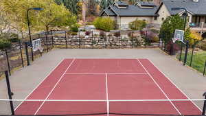 View of tennis court featuring basketball hoop