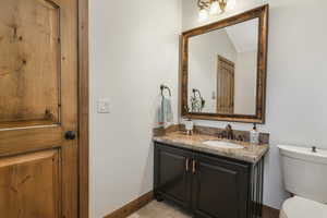 Bathroom featuring toilet, tile floors, large vanity, and vaulted ceiling