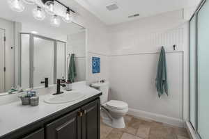 Bathroom featuring toilet, walk in shower, tile floors, and large vanity