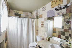 Bathroom with vanity, toilet, and tile walls