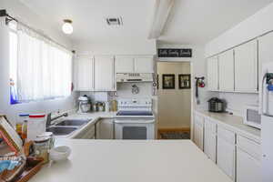 Kitchen with white cabinets, sink, and white appliances