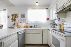 Kitchen with light tile floors, sink, stainless steel dishwasher, electric stove, and white cabinetry