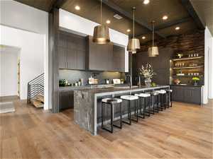 Kitchen featuring wood ceiling, light hardwood / wood-style floors, a kitchen bar, modern cabinetry, and backsplash
