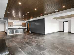 Spacious living room with custom tile floors, wet bar, sink, and wood ceiling