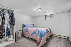 Carpeted bedroom with a textured ceiling and baseboard heating