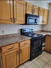 Kitchen with black appliances and light tile flooring