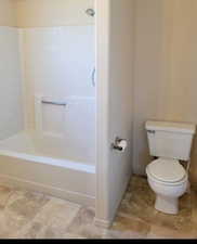 Bathroom featuring shower / bathing tub combination, tile floors, and toilet