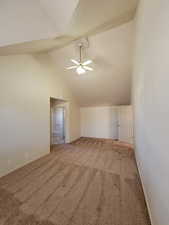 Carpeted spare room featuring ceiling fan and high vaulted ceiling