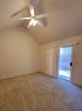 Carpeted empty room featuring lofted ceiling and ceiling fan