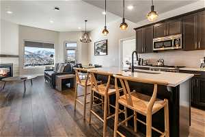 Kitchen with a kitchen island with sink, hanging light fixtures, dark brown cabinetry, and backsplash