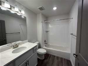 Full bathroom featuring toilet, oversized vanity, shower / bath combination, and wood-type flooring