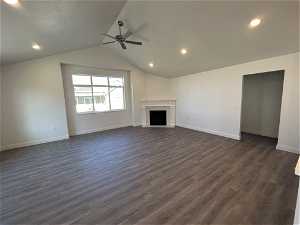 Unfurnished living room featuring dark hardwood / wood-style floors, ceiling fan, and vaulted ceiling
