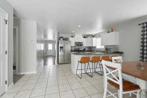 Kitchen with a wealth of natural light, kitchen peninsula, white cabinetry, and appliances with stainless steel finishes